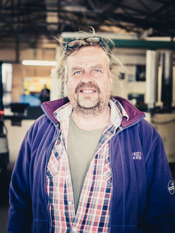 Ingolf Schwedes in Fleecejacke und kariertem Hemd, die Brille ins Haar geschoben, in der Werkhalle.